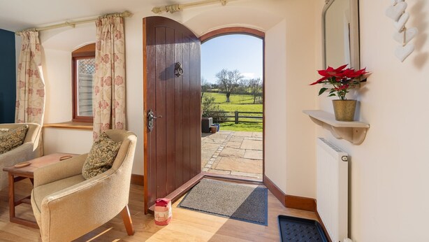 A room with a wooden door leading to a patio, a chair, a small table, a radiator, and a potted plant.