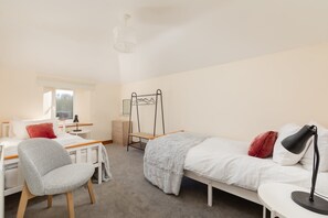 A bedroom with a bed, a desk, a chair, a bedside table, a lamp, a wardrobe, and a window. - Beautiful Cottage in Idyllic Somerset Countryside (Shepton Mallet)