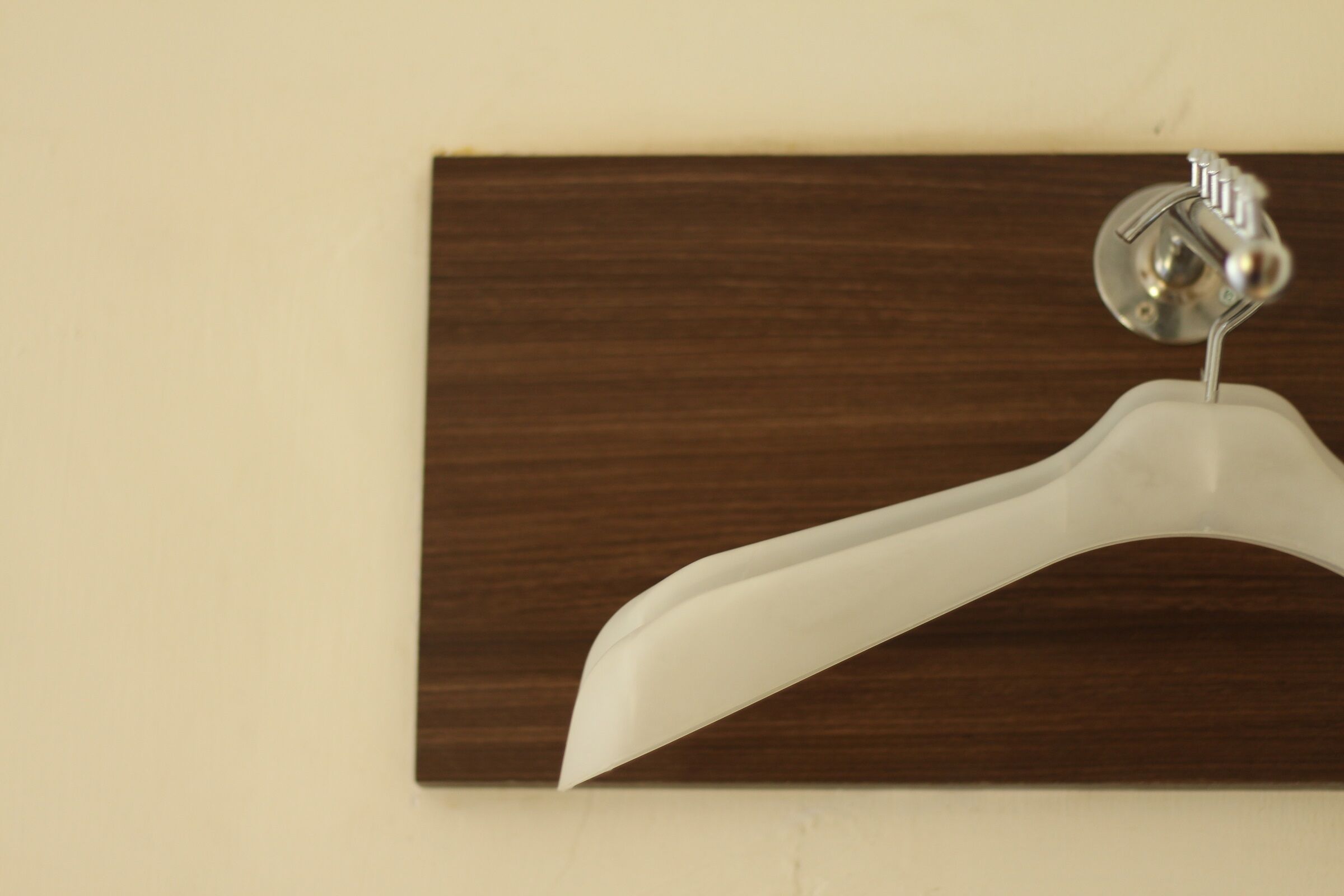 A white hanger mounted on a wooden panel.