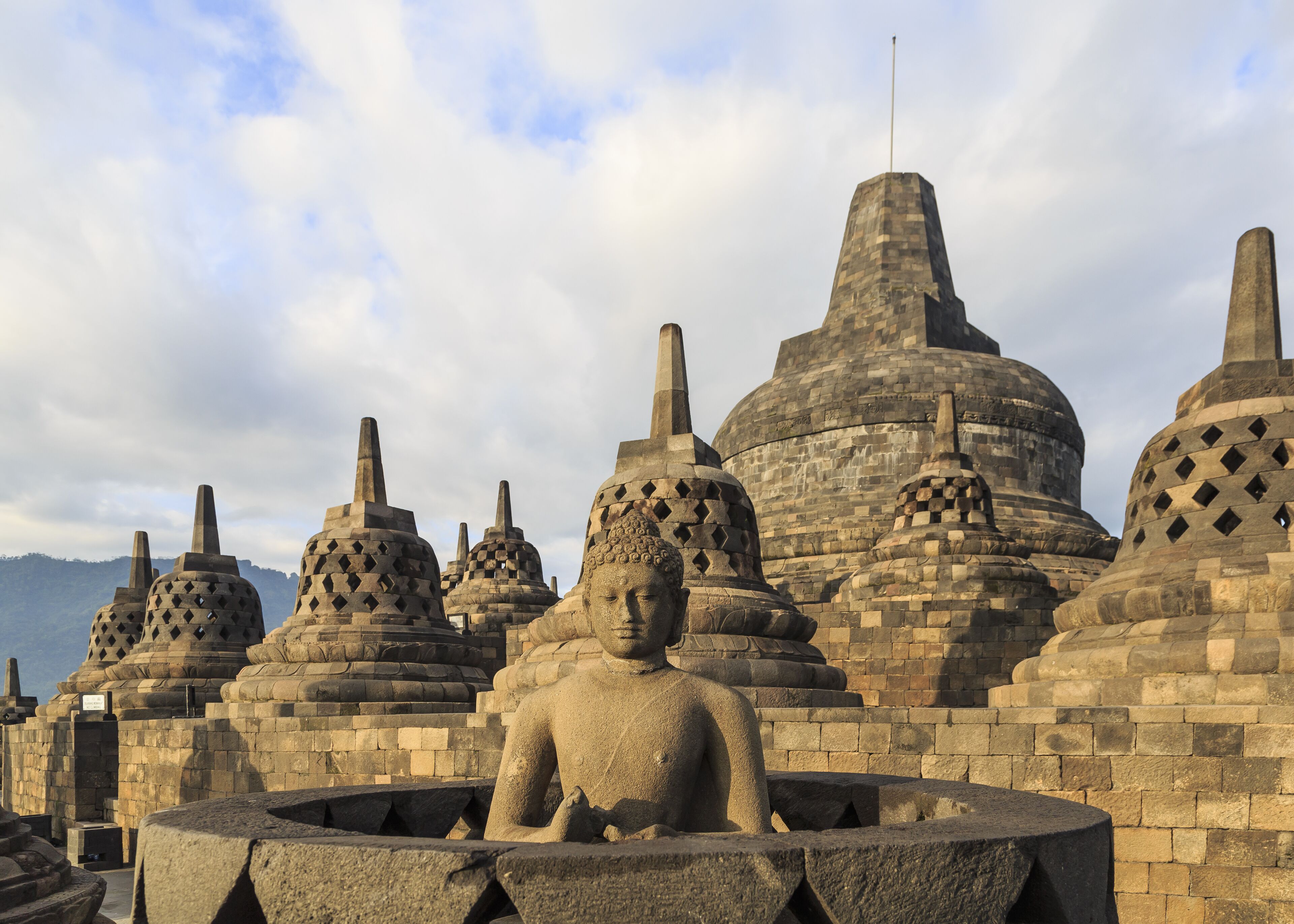 Un ensemble de stoupas en pierre et une statue de Bouddha assis.