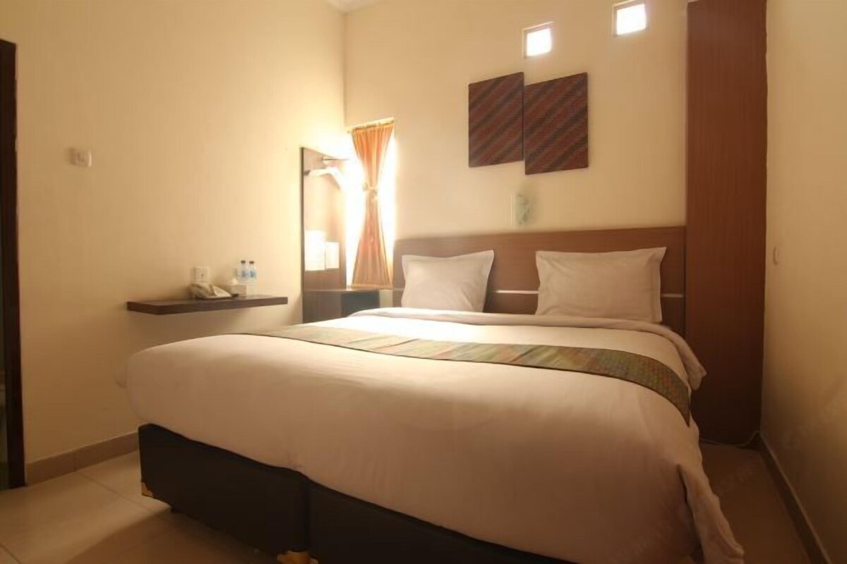 A hotel room with a large bed, a bedside table with a lamp, and a mirror on the wall.