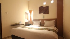 Una habitación de hotel con una cama grande, una mesita de noche, un espejo y dos lámparas de pared.