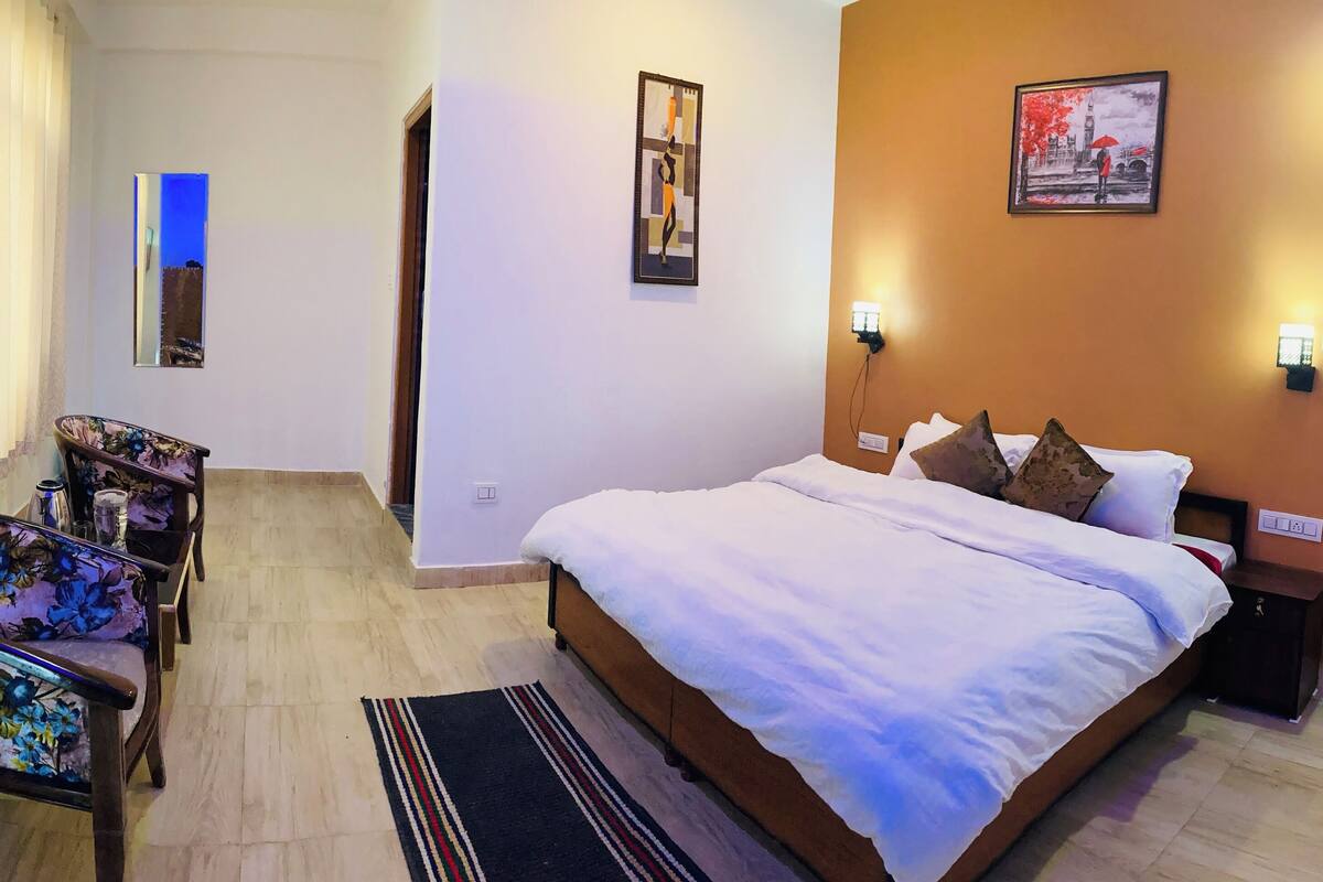 A hotel room with a bed, a chair, a small table, and a TV.