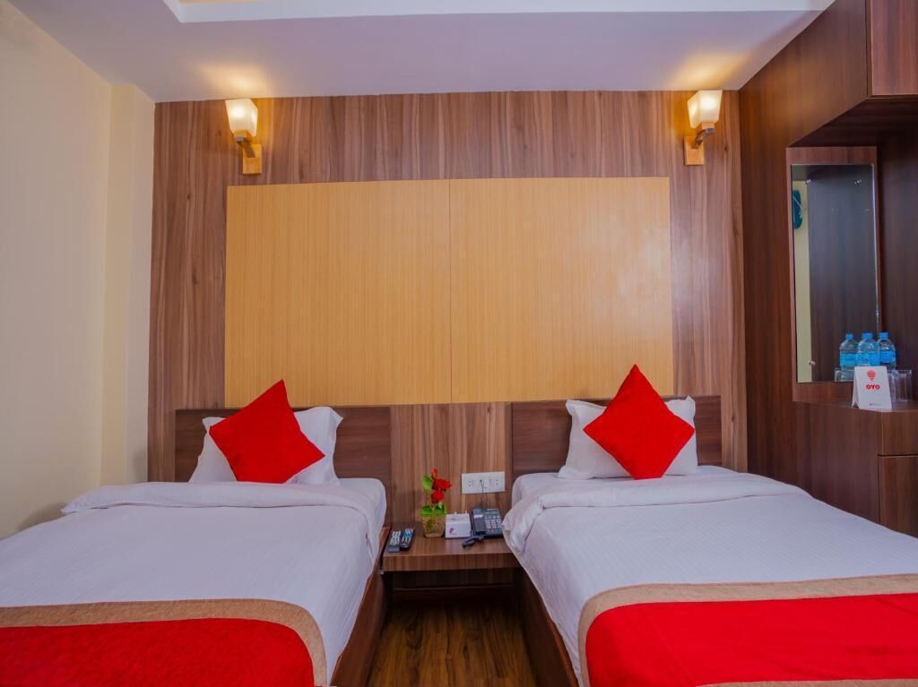 A hotel room with two beds, wooden headboard, bedside tables with lamps, and a mirror.