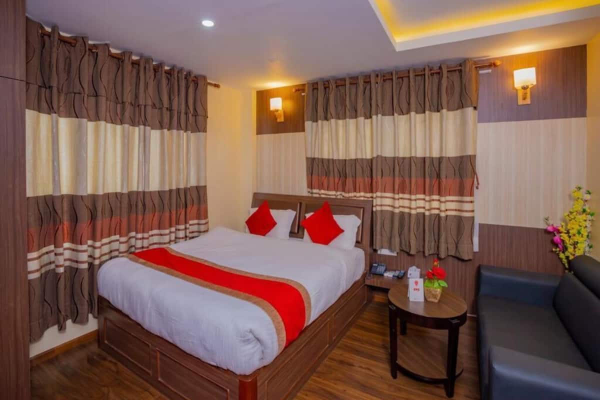 Ein Hotelzimmer mit Bett, einem kleinen Tisch, einer Couch und Vorhängen.
