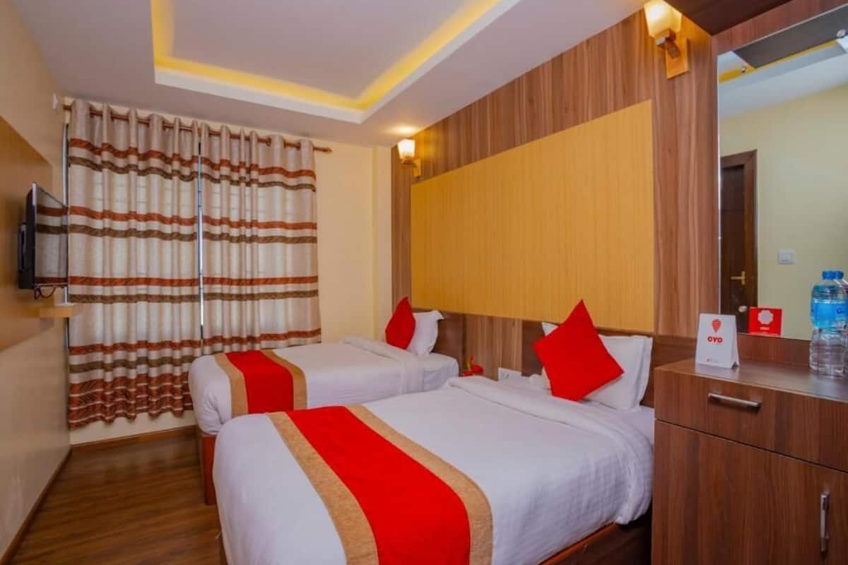 Ein Hotelzimmer mit zwei Betten, einem Holzkopfende, einem Fernseher und einer Minibar.
