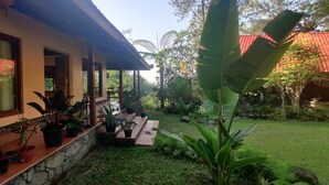 A house with a covered porch, potted plants, and a garden with a variety of greenery. - Private nature estate near Mt Merapi, Yogyakarta, stylish villa 4/6 persons (Kabupaten Sleman)