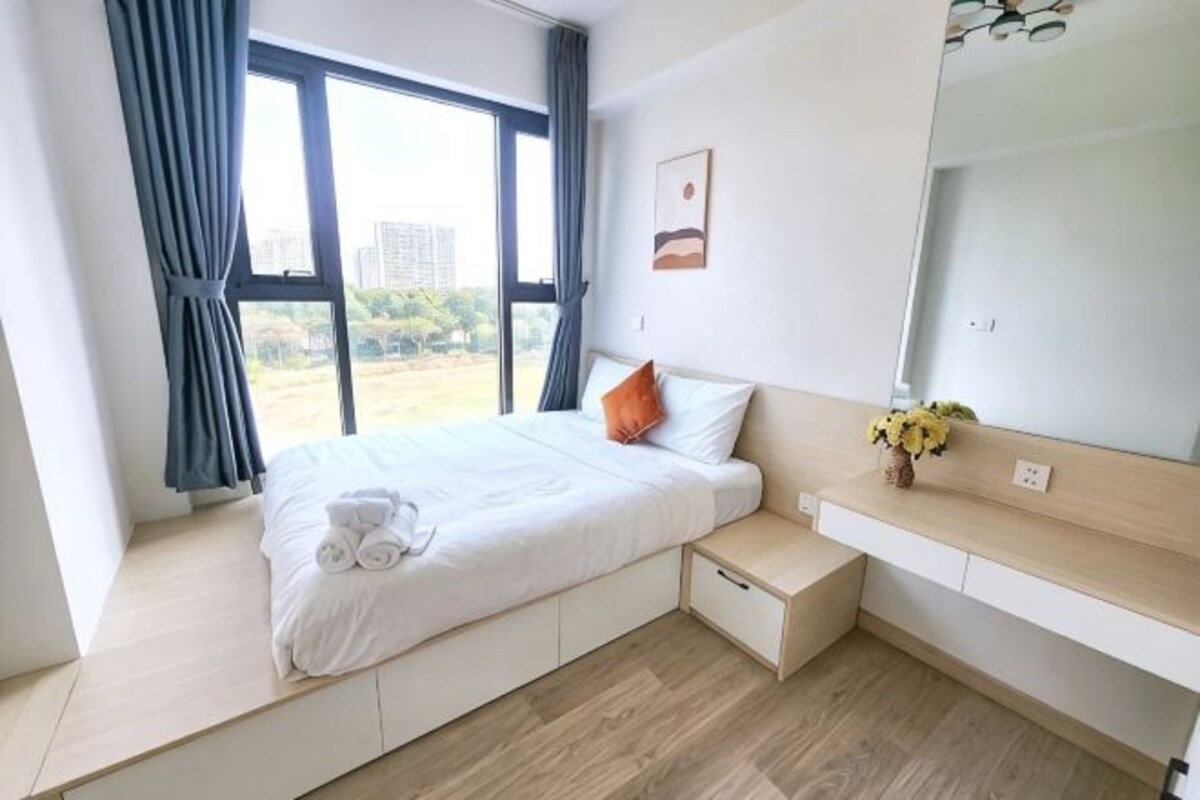 Ein Schlafzimmer mit Bett, Nachttisch, Spiegel und einem Fenster mit Vorhängen.