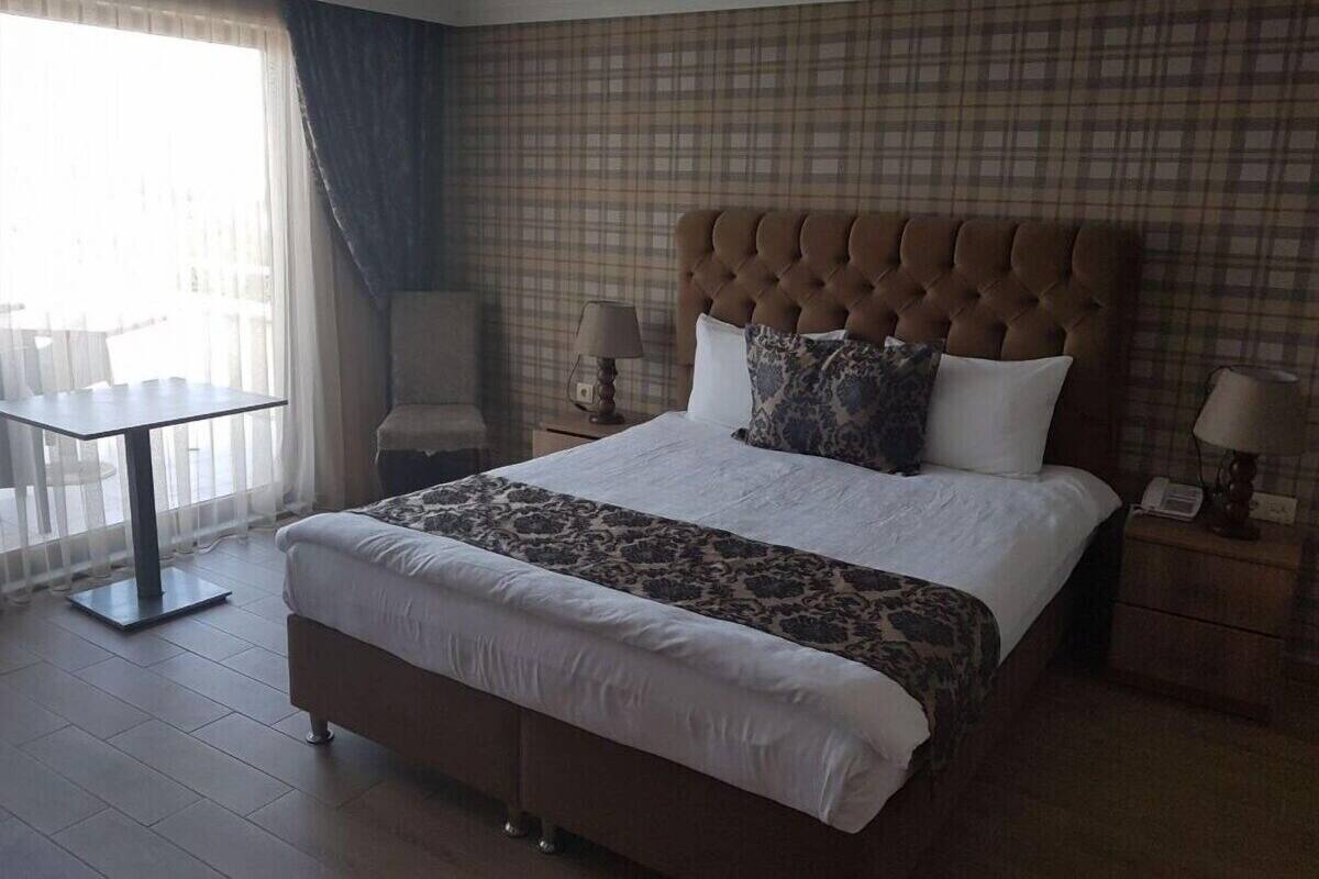 Una habitación de hotel con una cama grande, una mesita y una silla.