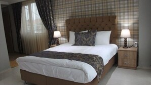 A hotel room with a large bed, two bedside tables, a headboard, and a plaid-patterned wall. - Seda Park Otel (Biga)