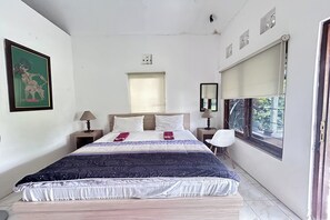 A bedroom with a bed, bedside tables, a window, and a wall-mounted mirror. - Carla Garden (Pakem)