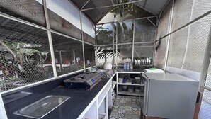 Una cocina compacta con encimera negra, un fregadero y una pequeña repisa con utensilios de cocina.