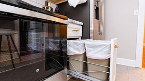 A compact kitchen with a built-in oven, a small countertop, and a stainless steel refrigerator. - Royal Respite: Green Kings & Grey Queens Hideaway! (Richmond)