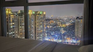 Une pièce dotée d’une grande fenêtre donnant sur une vue panoramique de la ville la nuit.