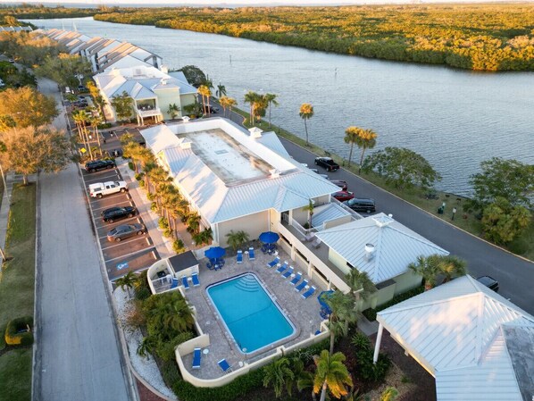 A resort with a swimming pool, lounge chairs, and a view of a water body.