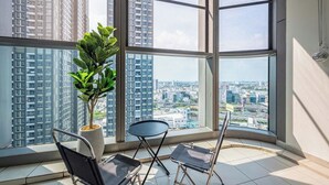 A high-rise apartment with large windows, a potted plant, and two chairs. - Landmark 81 - Saigon Luxury Apartment (Ho Chi Minh City)