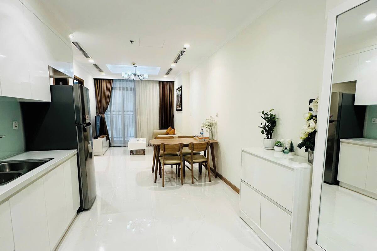 Une cuisine moderne avec des meubles blancs, une cuisinière encastrée et un coin repas comprenant une table et des chaises.