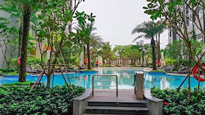 A swimming pool surrounded by lush greenery and palm trees, with steps leading into the water. - Landmark 81 - Saigon Luxury Apartment (Ho Chi Minh City)
