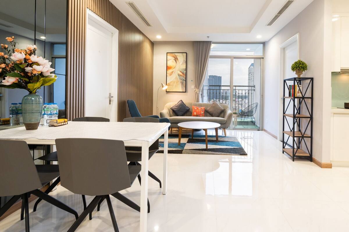 Un salon moderne comprenant un coin repas, un canapé, une table basse et offrant une vue sur la ville grâce à de grandes fenêtres.