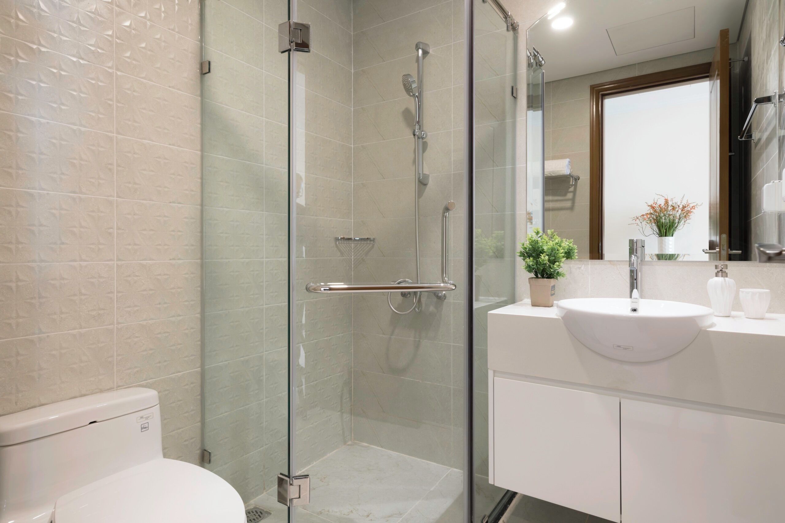 A modern bathroom with a glass-enclosed shower, a white sink, and a mirror above it.