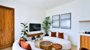 A modern living room with a sofa, a TV, a plant, and a kitchen area. - Elena Villa by Betterplace (Cemagi)