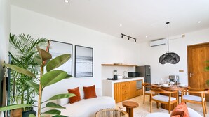 A modern living room with a sofa, dining table, and kitchen area. - Elena Villa by Betterplace (Cemagi)