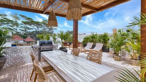 An outdoor patio with a grill, wicker furniture, and potted plants. - Elena Villa by Betterplace (Cemagi)
