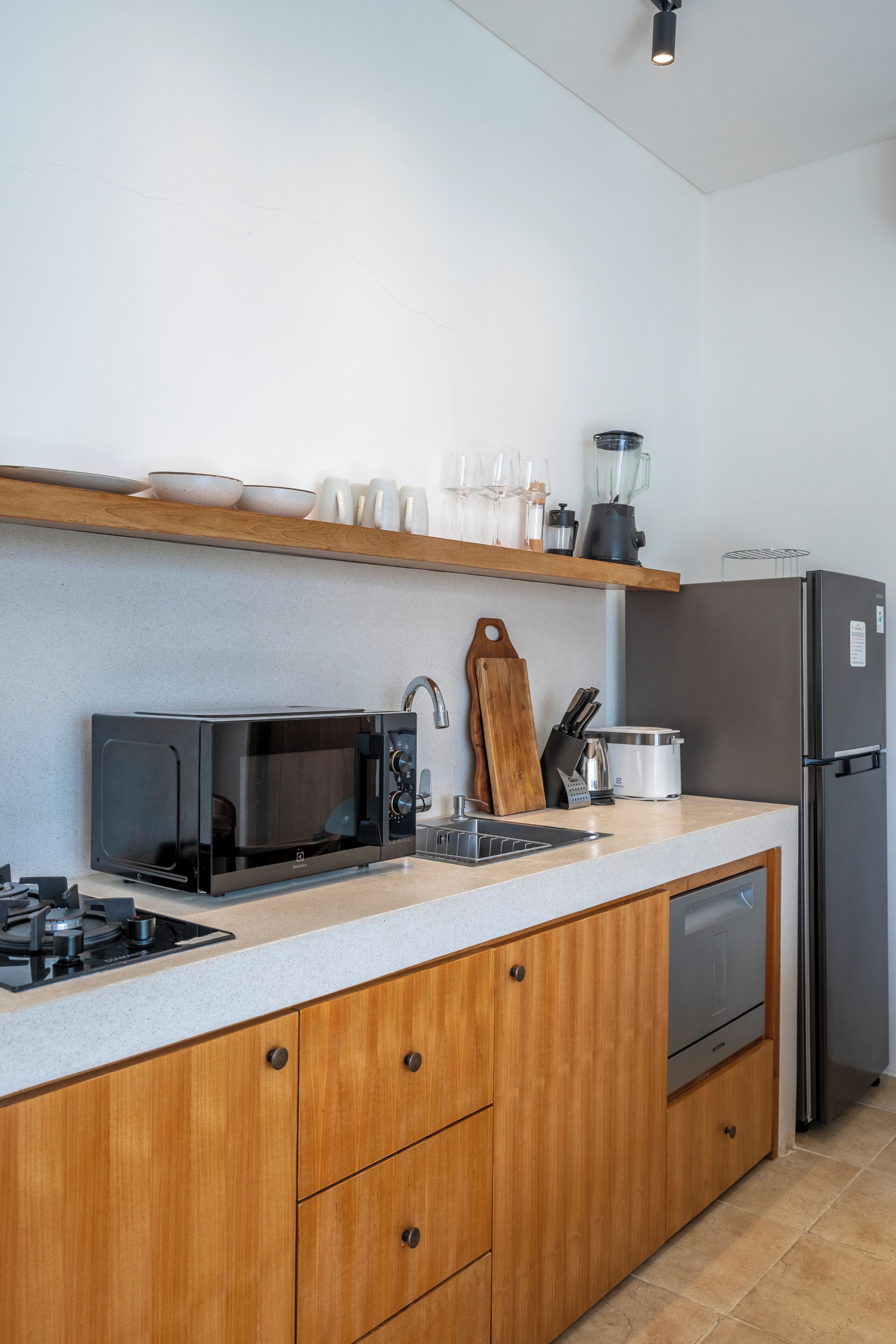 Una cocina moderna con microondas, estufa, fregadero, armarios de madera y refrigerador.