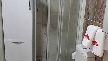 Een badkamer met een douchecabine van glas, een toilet met bloemenprint en een wit wastafel.