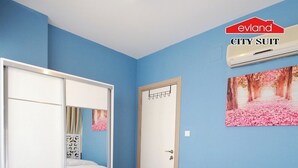 A bedroom with a bed, a wardrobe, a door, and a wall-mounted air conditioner. - EVLAND CİTY SUİT (Adana)
