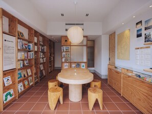 Eine Bibliothek mit Holzbögen, einem zentralen Tisch und Hockern.
