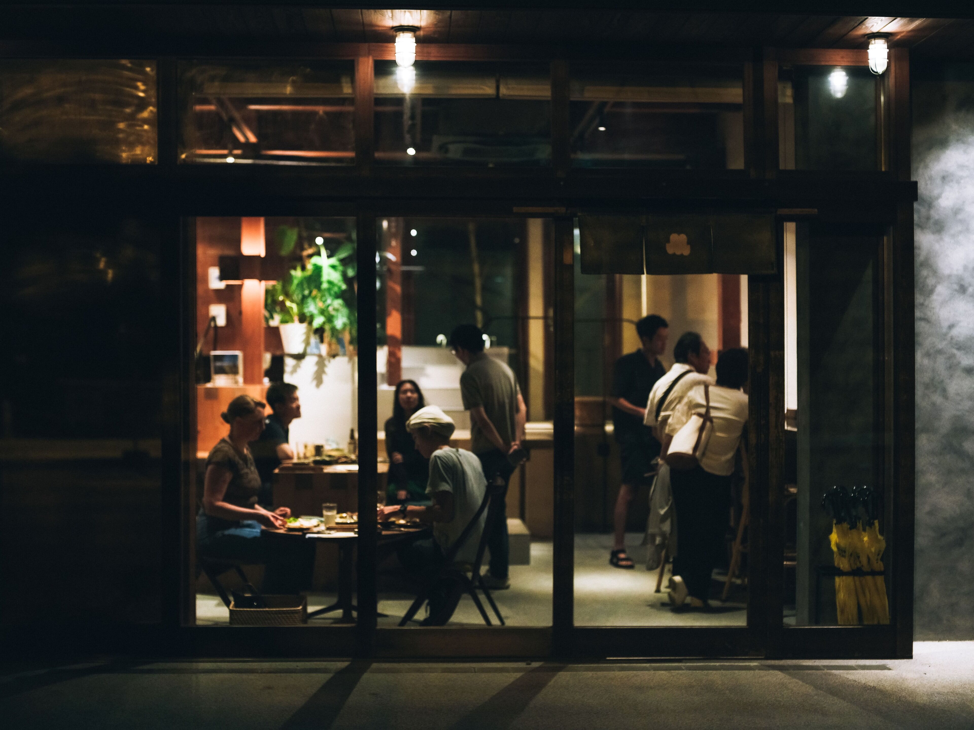 Un comedor interior con mesas y sillas, una barra y una planta colgante.