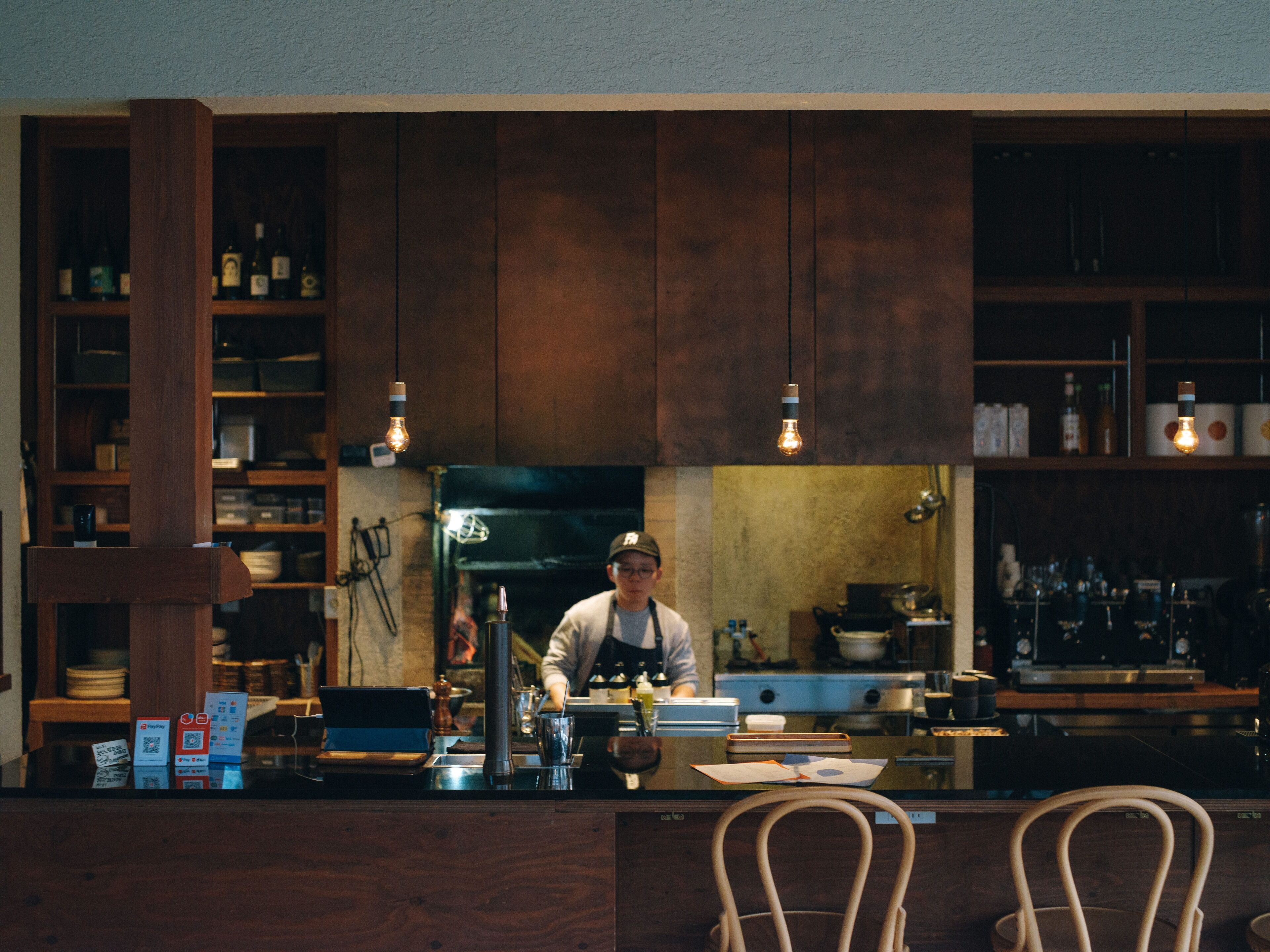 A bar area with wooden cabinets, a counter, and a person working behind the bar.