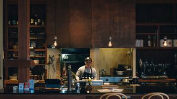 A bar area with wooden cabinets, a counter, and a person working behind the bar.