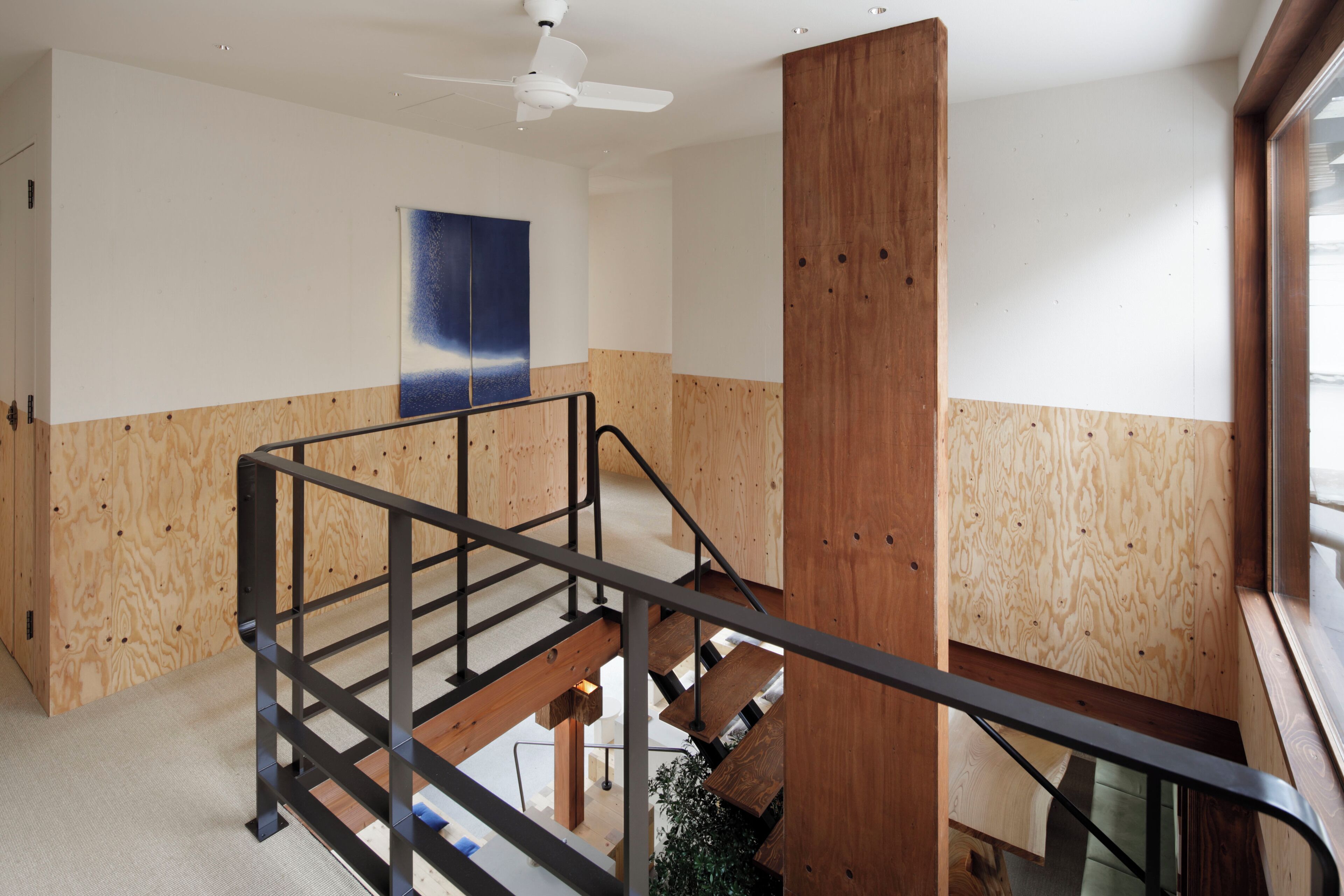 A modern interior with a wooden staircase, a ceiling fan, and a large abstract painting on the wall.