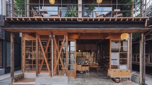 Un edificio de madera con balcón, ventanas amplias y un pequeño carrito en el exterior.