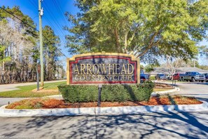 Une enseigne indiquant l’entrée du Arrowhead Country Club, avec un espace paysager aménagé devant.