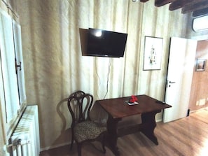 A room with a wooden table, a chair, a television mounted on the wall, and a door. - Ca Lirica Peace of Mind Just a few Steps From St Mark's Square (Venice)