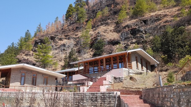 A two-story stone building with a wooden deck and stairs leading to a balcony. - Whispering Woods Resort (Thimphu)
