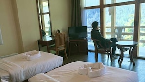 A hotel room with two beds, a TV, a desk, and a chair. - Whispering Woods Resort (Thimphu)