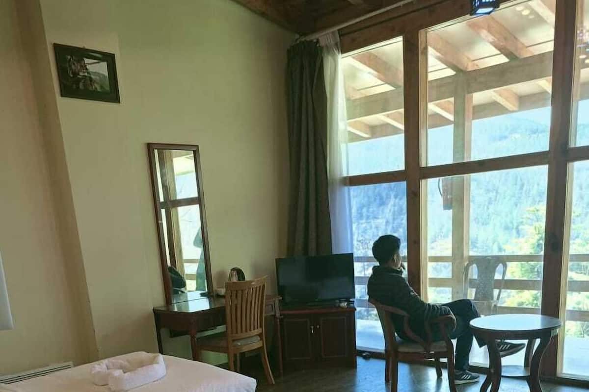 A hotel room with two beds, a TV, a desk, and a chair.
