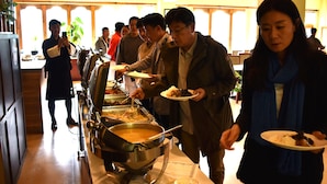 A buffet setup with multiple food stations and people serving themselves. - Whispering Woods Resort (Thimphu)