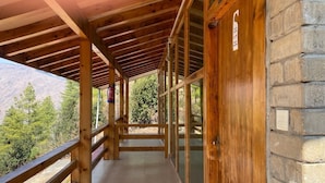 A covered wooden corridor with a view of a mountainous landscape. - Whispering Woods Resort (Thimphu)