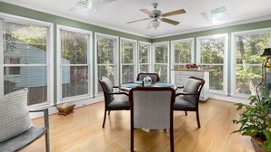 Un coin repas avec une table ronde, quatre chaises et un ventilateur de plafond.