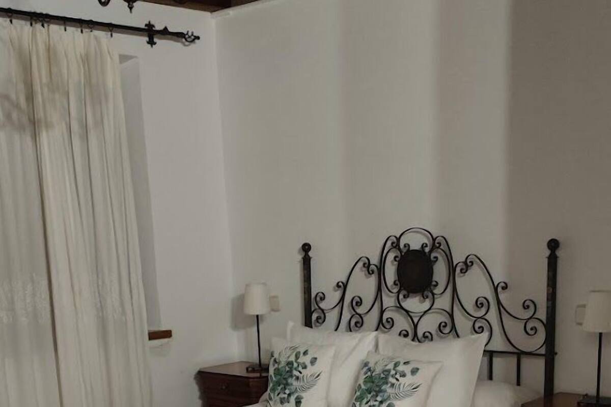 Quarto com cama, cadeira de madeira, candelabro e piso de azulejos.