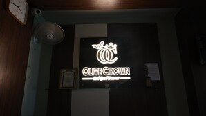 A sign with the text "OLIVE CROWN" and a logo above it. - Hotel Olive Crown (Lucknow)