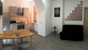 Un espace de vie compact comprenant une cuisine, un coin repas et un canapé noir.