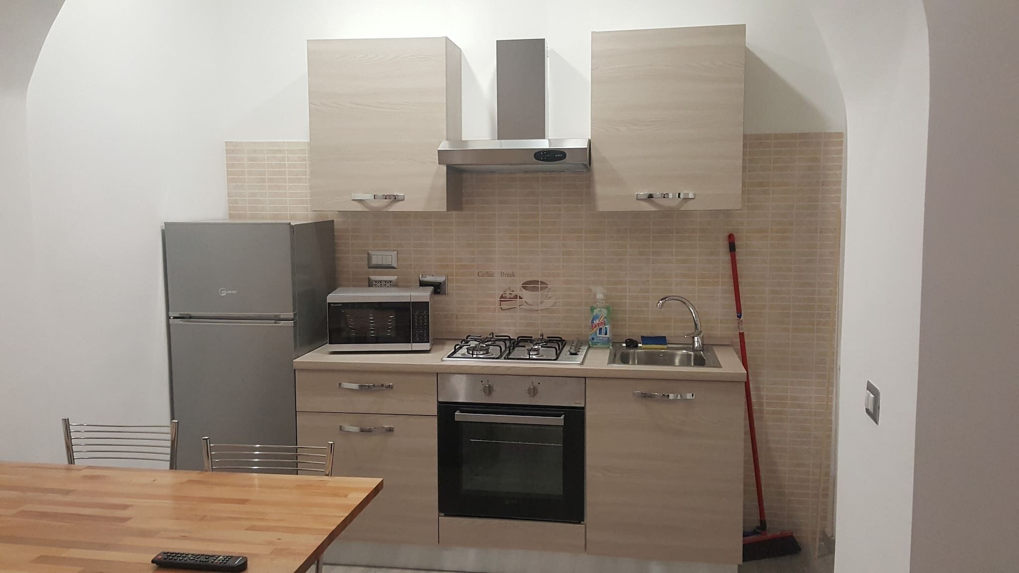 A compact kitchen with a refrigerator, microwave, stove, oven, and a coffee maker.
