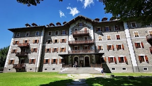 A multi-story stone building with balconies and a central entrance. - Grand Hotel Ceresole Reale Studio Apartment (Ceresole Reale)