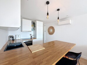 Une cuisine moderne avec un plan de travail en bois, un four encastré, un évier et une chaise noire.